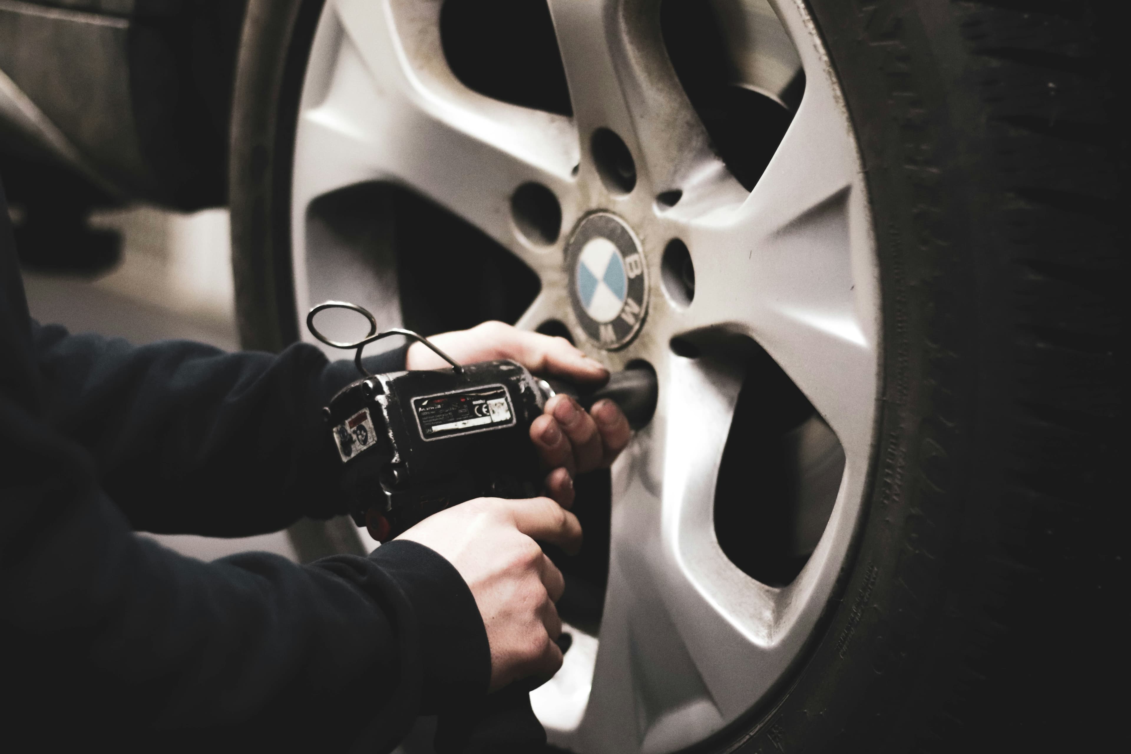 picture of a mobile mechanic using a tool to remove a tire from a car